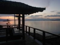 una puesta de sol sobre el agua con un banco en un muelle en Pousada Casa Atlântica, en Angra dos Reis