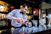 Ein Mann steht an einer Bar und bereitet einen Drink vor. in der Unterkunft Park Hotel Grenoble - MGallery Collection in Grenoble