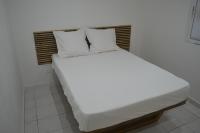 a bed with white sheets and pillows in a room at Plumeria Hébergement Tiare in Grand-Bourg