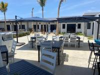 een terras met tafels, stoelen en parasols bij Las Palmas Hotel - Cerritos Beach in El Pescadero