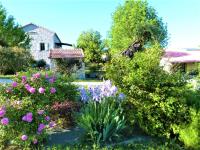 a garden with flowers and a house in the background at CHAMBRES D&#39;HOTES 2 à 4p ou GITE DE GROUPE 15p, 7 ch, 6 sdb, parc et salle de réception in Villeneuve-de-Berg