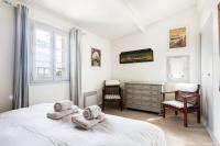 a bedroom with a bed and two chairs and a dresser at Appartement de l&#39;ilot. La fenêtre de Vauban. in Saint-Martin-de-Ré
