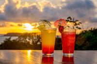 two cocktails on a table with a sunset in the background at El Faro Containers Beach Hotel in Manuel Antonio