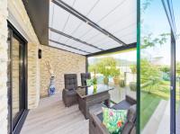 a patio with a glass roof and a table and chairs at Appartement Villa Quietude in Bagnols-en-Forêt