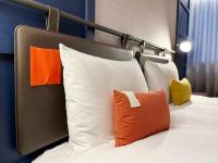 a bed with white pillows and an orange pillow at OLAH Poshtel - Taichung Station in Taichung