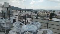 a balcony with tables and chairs and a view of a city at Jag Niwas Guest House & pure veg restaurant in Udaipur