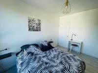 a bedroom with a bed and a desk with a lamp at Appartement Charmant Cocon Plus in Croix