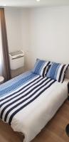 a bed with blue and white striped sheets in a room at Escapade Niortaise - Studios climatisés hyper-centre de Niort in Niort