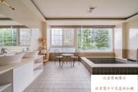 a bathroom with a tub and a table and chairs at Cingjing Florence Resort Villa in Ren&#39;ai