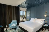 Un dormitorio con una cama y una silla azul. en Hotel Botanica- Limited Edition By Fattal, en Haifa