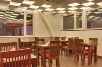 a restaurant with wooden tables and chairs and windows at Hotel Grand Godwin -Near Connaught Place- Free Airport Pick-Up in New Delhi