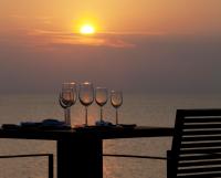 three wine glasses sitting on a table with the sunset at Pullman Phuket Arcadia Naithon Beach in Nai Thon Beach