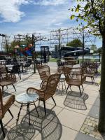 Un grupo de sillas y mesas con un patio de juegos. en LUXUS Cube Ferienhaus Chalet am See mit Schwimmbad in Lathum NL, en Lathum
