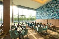 BharūchにあるHyatt Place Bharuchのテーブルと椅子があり、壁一面に窓があるレストラン