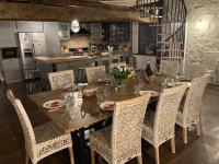 Una mesa de comedor con sillas y una cocina. en Le Clos Bô-m, en Marignieu