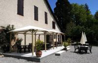 a building with tables and umbrellas in front of it at Glamping at Camping La Source in Saint-Pierre-dʼArgençon