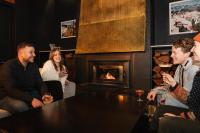 Un grupo de personas sentadas alrededor de una mesa en un bar con chimenea. en Lakeside Falls Creek, en Falls Creek
