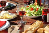 a wooden table with a salad and a glass of wine at Glamping at Camping La Source in Saint-Pierre-dʼArgençon