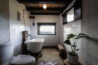 a bathroom with a white tub and a toilet and a plant at Sunny Room in Jiufen