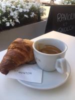 a cup of coffee and a croissant on a table at Duplex vue mer 50m de la plage des Sablettes in Menton