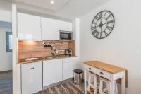 une cuisine avec des placards blancs et une horloge murale dans l&#39;établissement Appartement Feige - Welkeys, à Megève