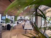 a restaurant with white tables and chairs and a plant at Westotel Le Pouliguen in Le Pouliguen