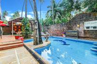 Una gran piscina en un patio con palmeras. en FabExpress Golden Nest Deluxe - Nr Calangute Beach, en Old Goa