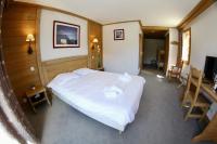 a bedroom with a white bed and a desk at Le Vancouver in La Plagne