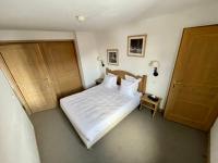 a bedroom with a bed with white sheets and two doors at Le Vancouver in La Plagne