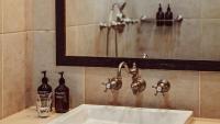 a bathroom sink with a mirror and two bottles on it at Maison Saintonge in Paris