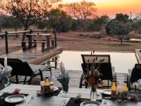 a table and chairs on a deck with a view of a field at Roaring Sky Base Camp in Baviaanspoort