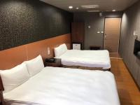 two beds in a room with white sheets at Long Siang Hotel in Kaohsiung