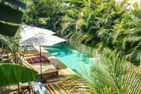 una piscina con sillas, sombrilla y palmeras en Hotel Gallo de Mar, en Puerto Escondido