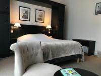 a hotel room with a bed and a chair at Logis Hôtel-Restaurant Les Airelles in Neufchâtel-en-Bray