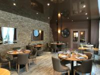 a restaurant with tables and chairs and a brick wall at Logis Hôtel-Restaurant Les Airelles in Neufchâtel-en-Bray