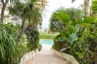 a path through a garden with a swimming pool at VILLA LE MAS D&#39;AZUR BY ESTATESCANNES in Vallauris