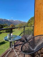 a table and chairs on a deck with mountains in the background at Roots Svaneti &#39; რუთს სვანეთი in Lentekhi