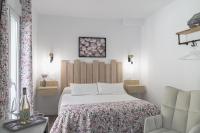 a white bedroom with a bed and a chair at Casa Rural Las Cuevas de Setenil in Setenil