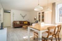 a dining room and living room with a table and chairs at Residentie Californië in De Koog