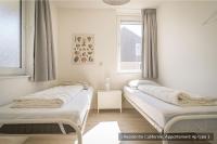 two beds sitting in a room with a window at Residentie Californië in De Koog