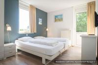 two beds in a room with two windows at Residentie Californië in De Koog