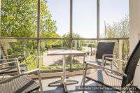 a balcony with chairs and a table and a large window at Residentie Californië in De Koog