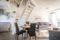 a dining room and living room with a table and chairs at Residentie Californië in De Koog