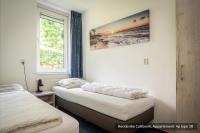 two beds in a room with a picture on the wall at Residentie Californië in De Koog