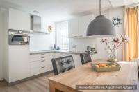 a kitchen with a wooden table with a vase of fruit at Residentie Californië in De Koog