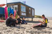 a group of people sitting in the sand on the beach at Residentie Californië in De Koog