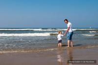 a man and a little girl standing on the beach at Residentie Californië in De Koog