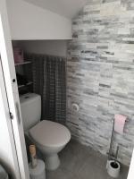 a bathroom with a white toilet and a tile wall at Studio entre Clohars Carnoet et Doelan in Clohars-Carnoët