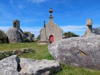 a small church with a red door in a field with rocks at Holiday home with sea views, Plounéour-Brignogan-Plages in Plounéour-Trez