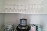 a shelf with plates and glass vases and cups at Le Jules Val - Studio cosy en résidence + Parking + Wi-fi in Évry-les-Châteaux